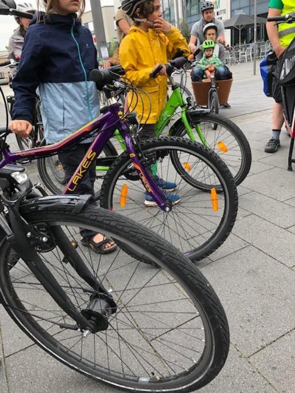 3 Fahrräder mit Menschen und ein Lastenrad mit Kind